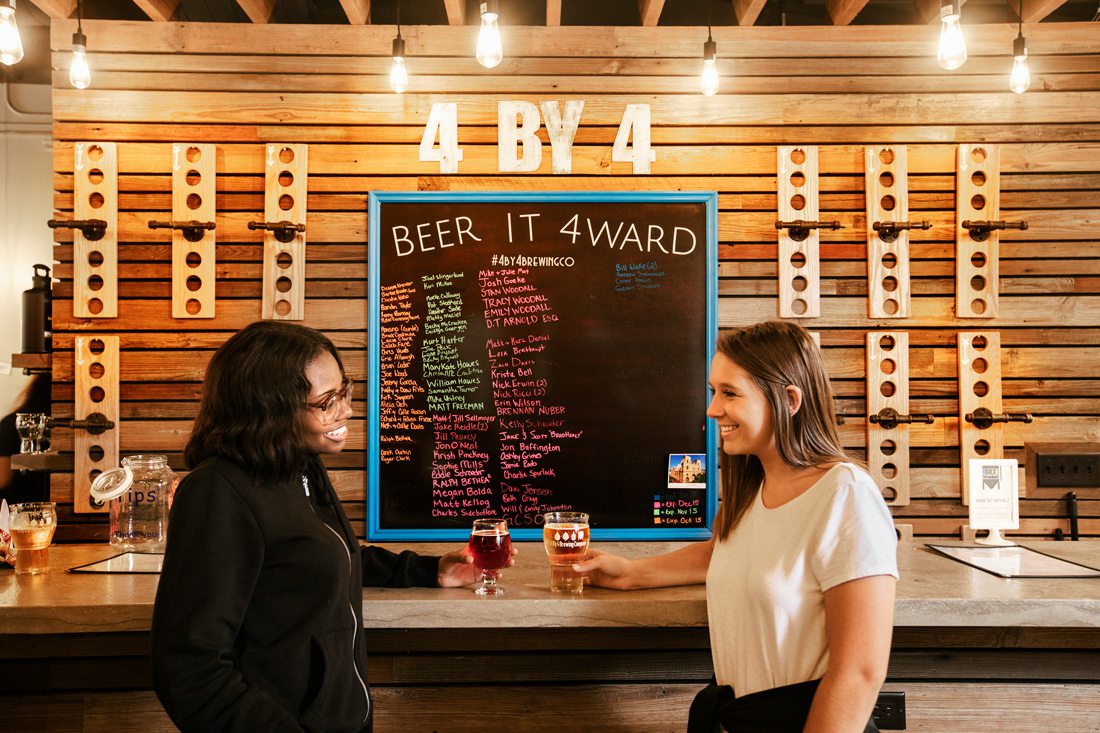 Two women at the bar drinking beer at 4 By 4 Brewing Company