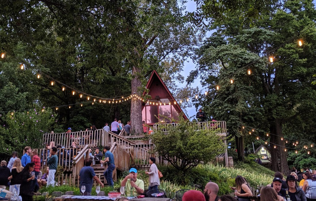 A frame home with lights and people hanging out