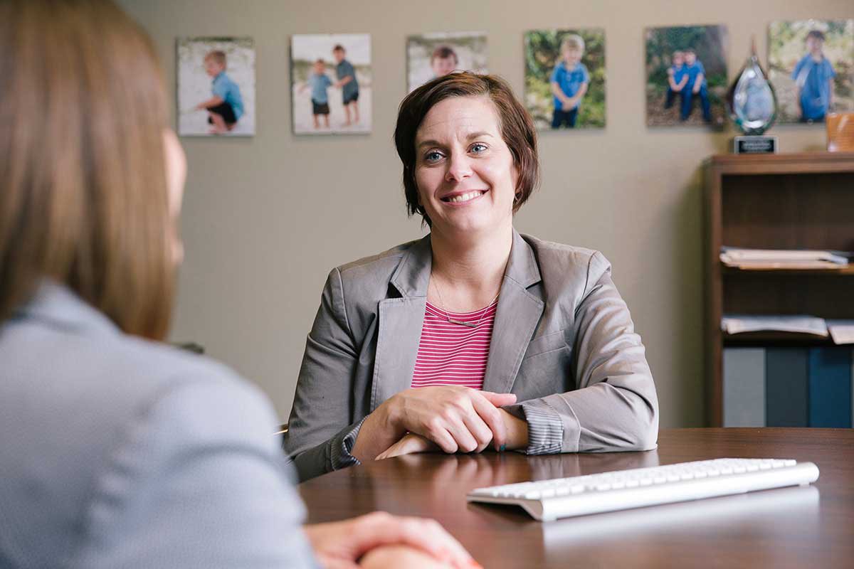 Amanda sits at her desk across from a client, smiling