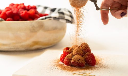 Sprinkling Askinosie Chocolate Cocoa Powder on raspberries