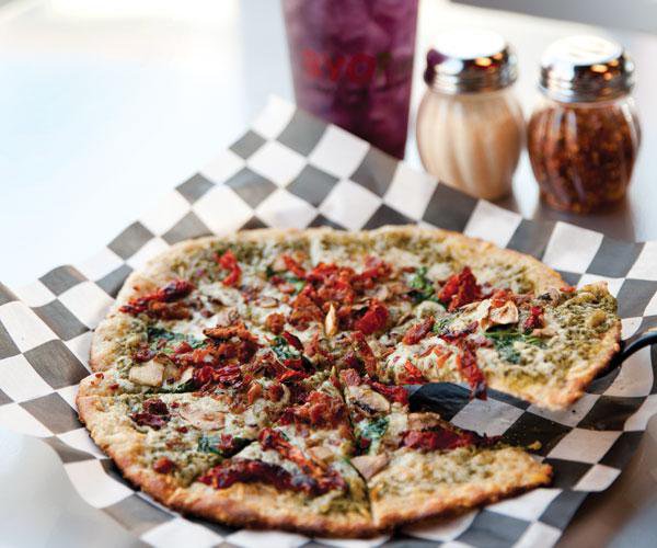 A wheat crust pizza topped with basil pesto, Parmesan and asiago cheeses, spinach, sun-dried tomatoes, mushrooms and bacon.