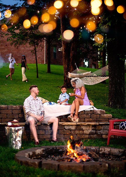 Young family enjoying s'mores by a backyard fire pit