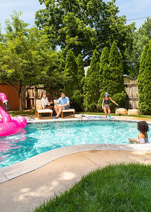 Young families lounging poolside in a backyard