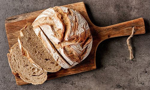 Loaf of sliced rustic fresh bread on a wooden cutting board