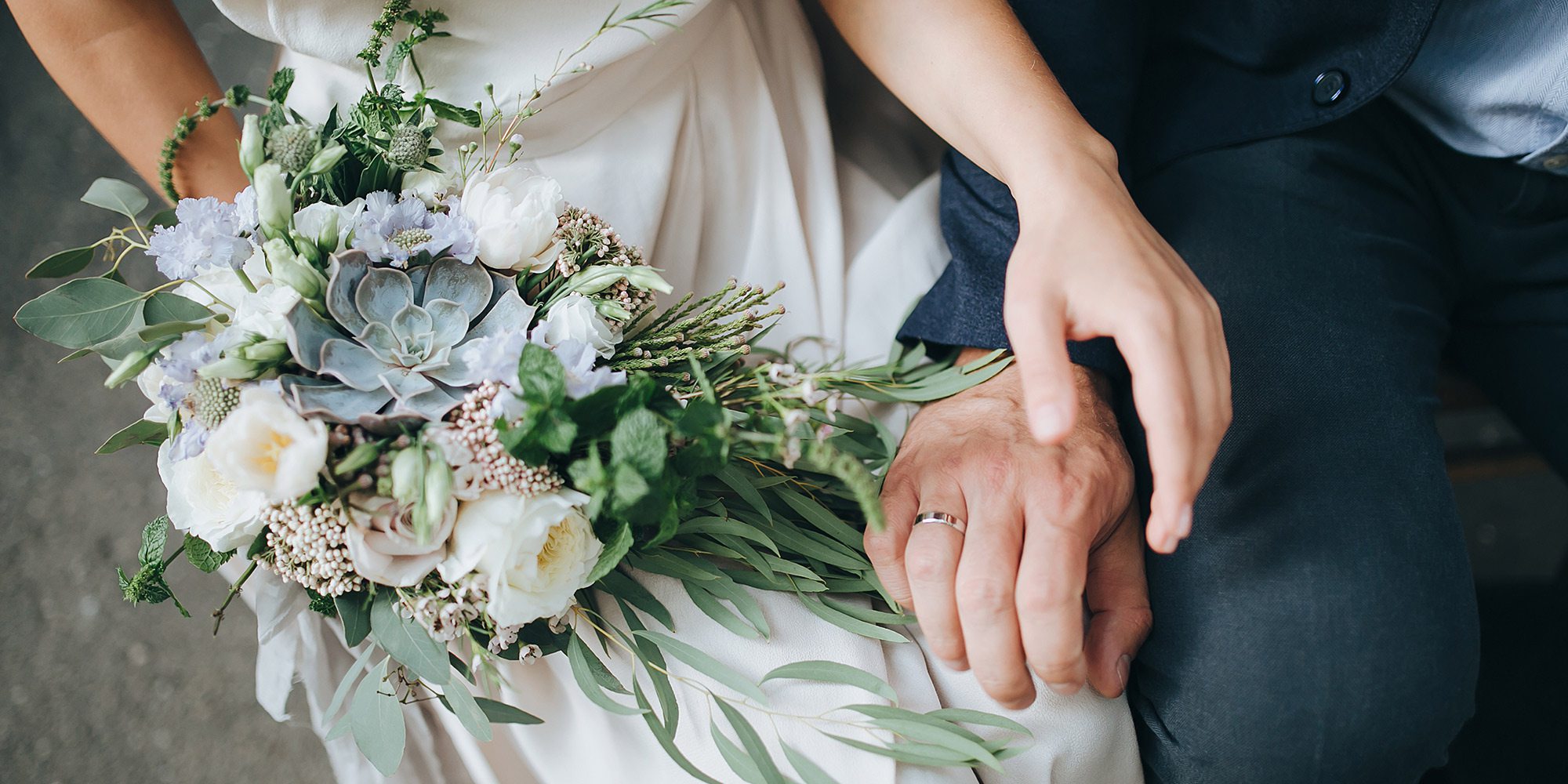 closeup of bride and groom's hands and bridal bouquet