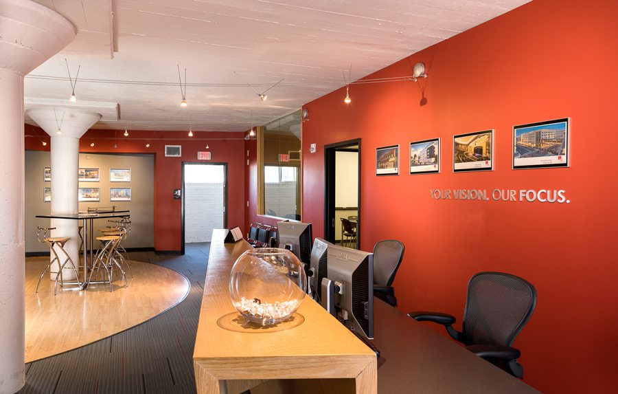 Bright red wall in modern office with long wood desks