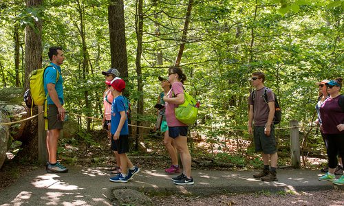 Man giving instructions to a group of people while on a hike in the woods