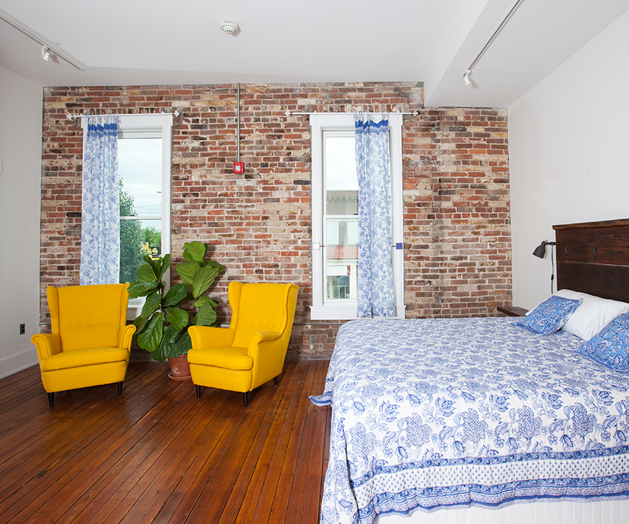 The Jaipur, India room has subtle Indian details and an exposed brick wall housing windows showing a view of C-Street.