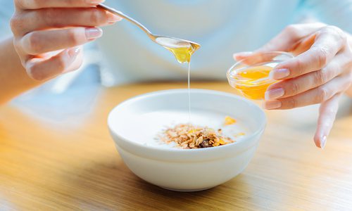 Woman drizzling honey over her bowl of oatmeal