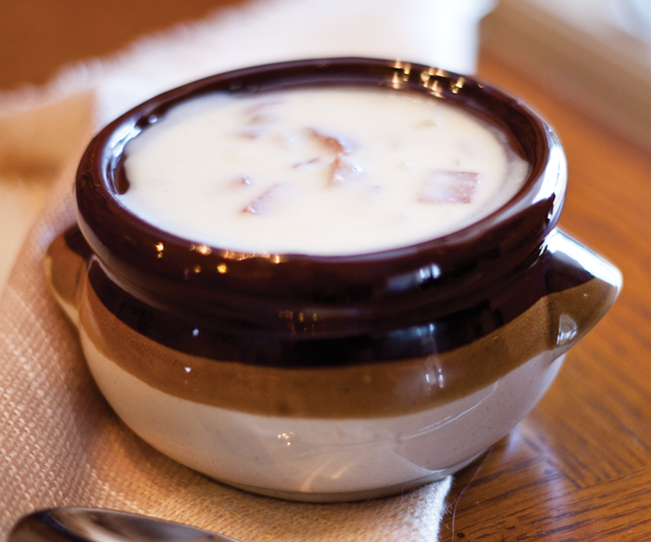 The creamy potato soups sits in a ceramic bowl