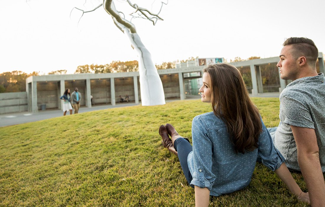 Couple sitting on the lawn outside Crystal Bridges in Bentonville AR