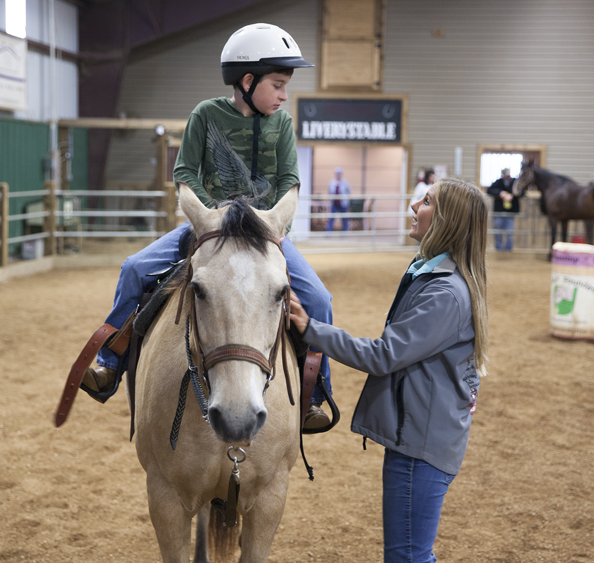 Senior arena instructor Loryn Barclay helps Karson Robb ride his horse.