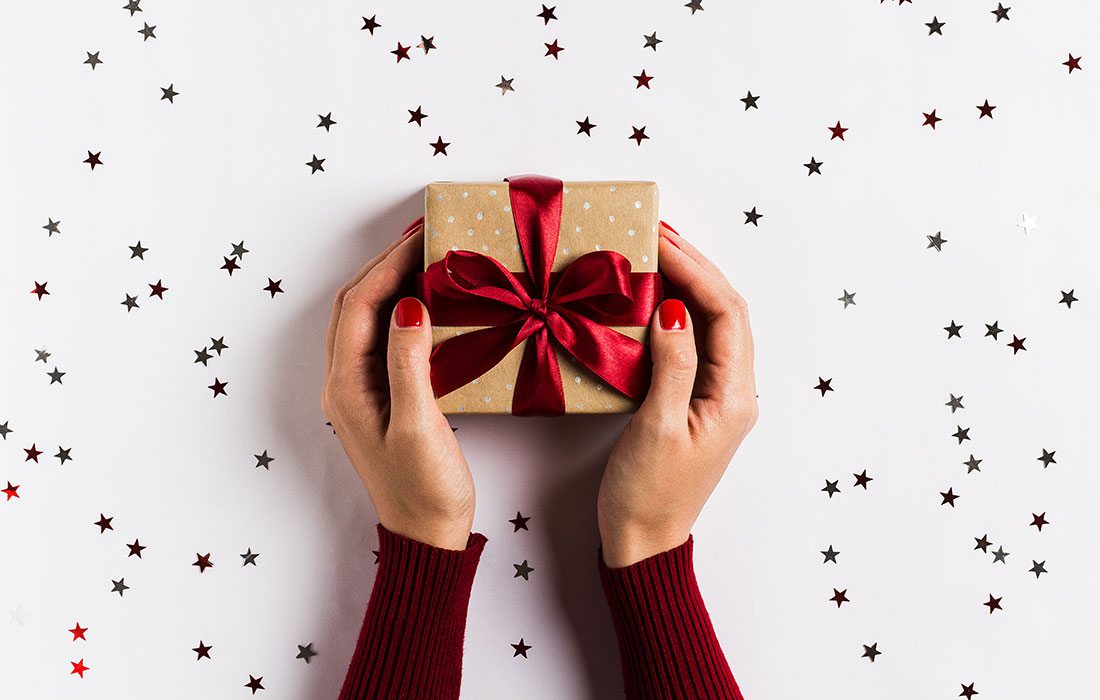 Woman's hands gifting a Christmas present