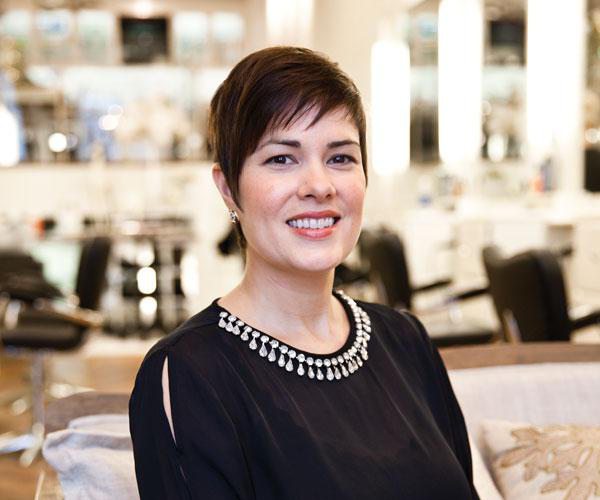 Pretty dark haired woman with pixie cut sitting in a bright, modern salon