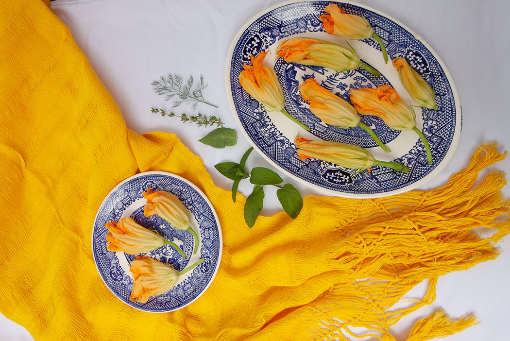 Squash blossoms laid out on blue china plates