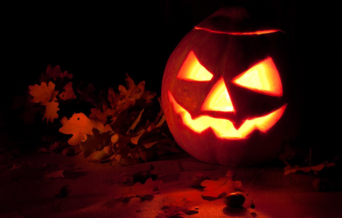 Jack O' Lantern with fallen leaves Shutterstock image.