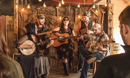 A group of people play their instruments and open their mouths to sing before an audience