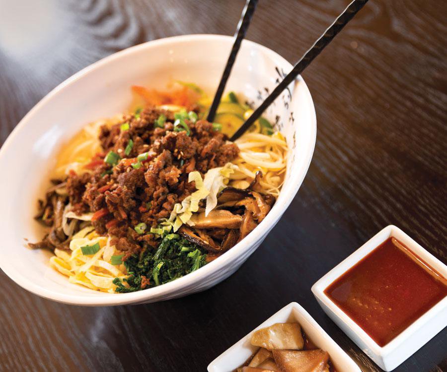 Bibimbap served with meat, veggies and sauce.