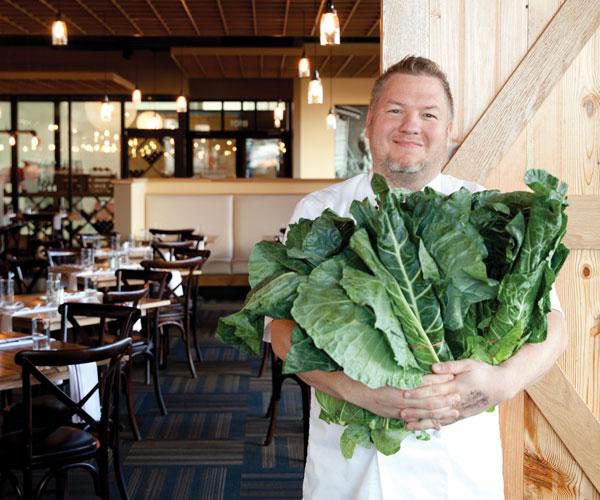 Chef holding greens inside farmhouse style restaurant