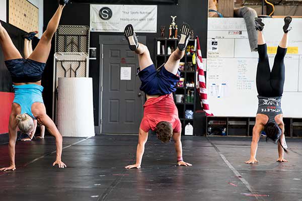 Nathan does a hand stand with two colleagues