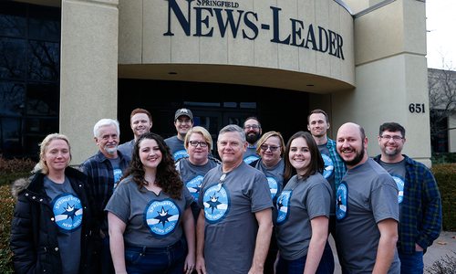 The news staff in front of their building