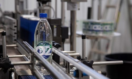 OzWater bottle on conveyor belt in Deer Lake Partners bottling plant.