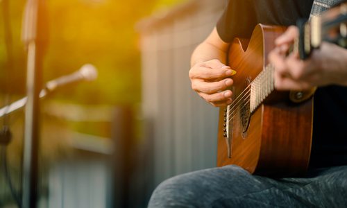 Closeup of someone playing an acoustic guitar outside