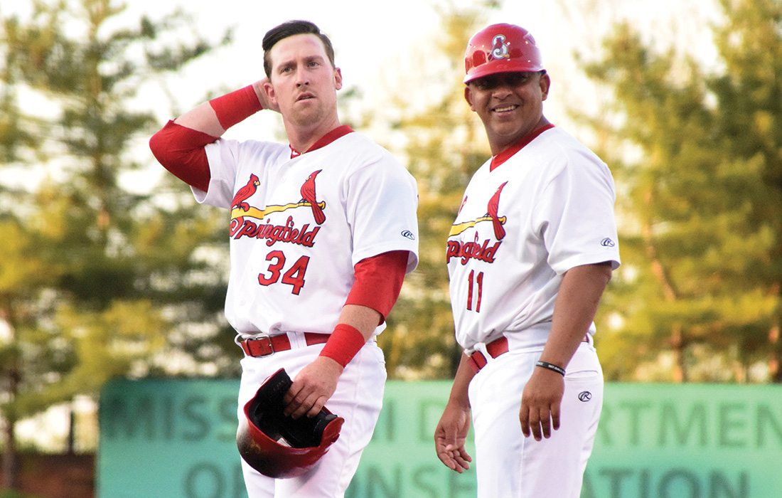 Coach Jobel Jimenez and John Nogowski stand of the field in their Cardinals uniform.