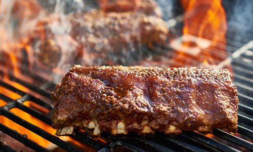 Rack of ribs cooking over a flame on the grill