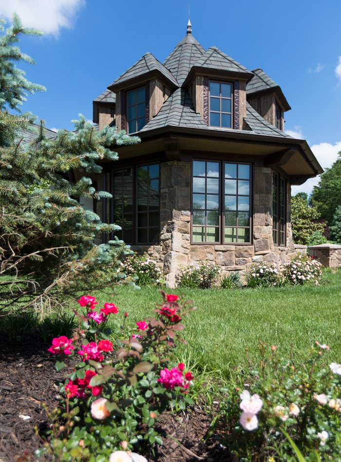 Tudor style home tower with windows and landscaping.