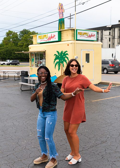 Two young girls doing the hula outside a Pineapple Whip cart in Springfield MO