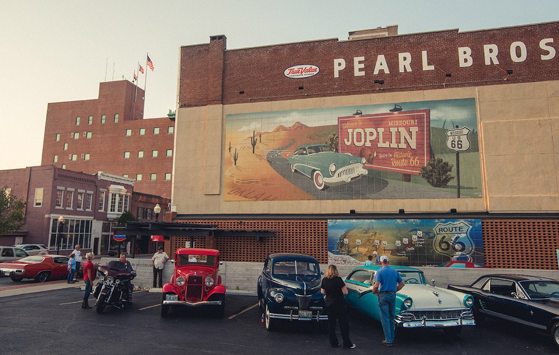 Classic cars sitting in front of the Route 66 mural in Joplin MO