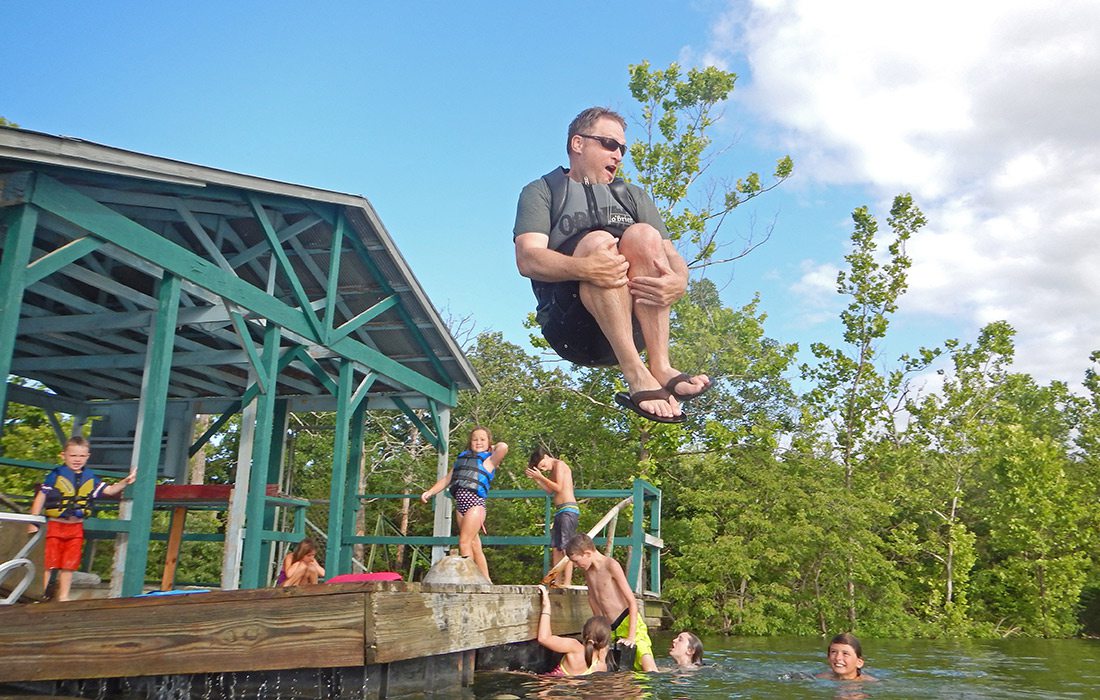 Father doing a cannon ball of the dock at Table Rock Lake in Branson MO