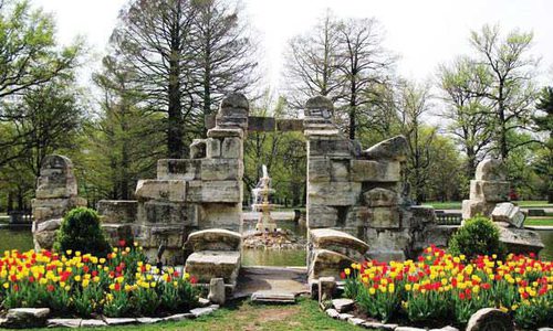 The stone gateway to Tower Grove Park blooms with tulips and the green grass surrounding