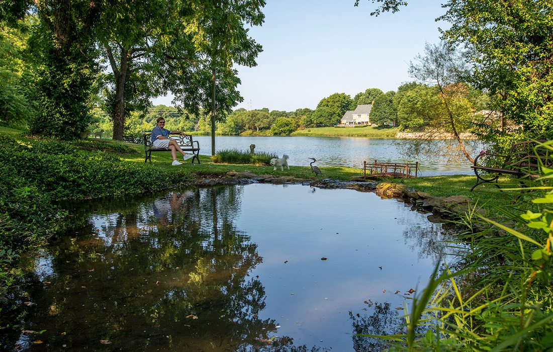 Pete Garrett sits by the picturesque spring on his yard that feeds one of the neighborhood lakes.