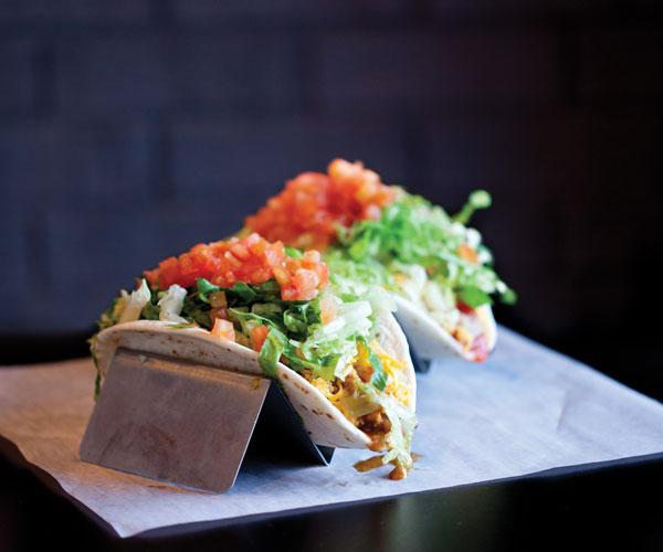 Colorful tacos with cheese, lettuce, onions and tomatoes.