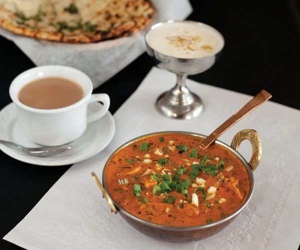 Indian meal with curry sauce, rice, naan and tea.