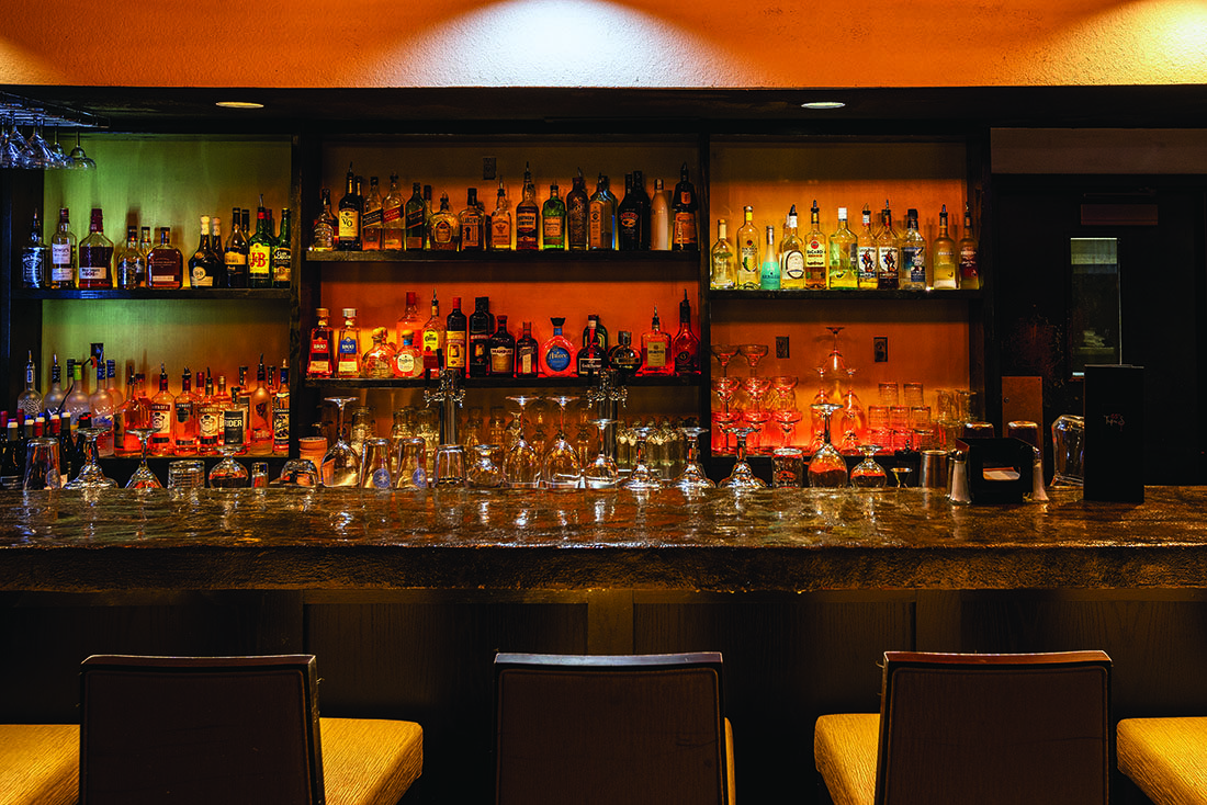 A bar with dark wood and heavy glass bottles.