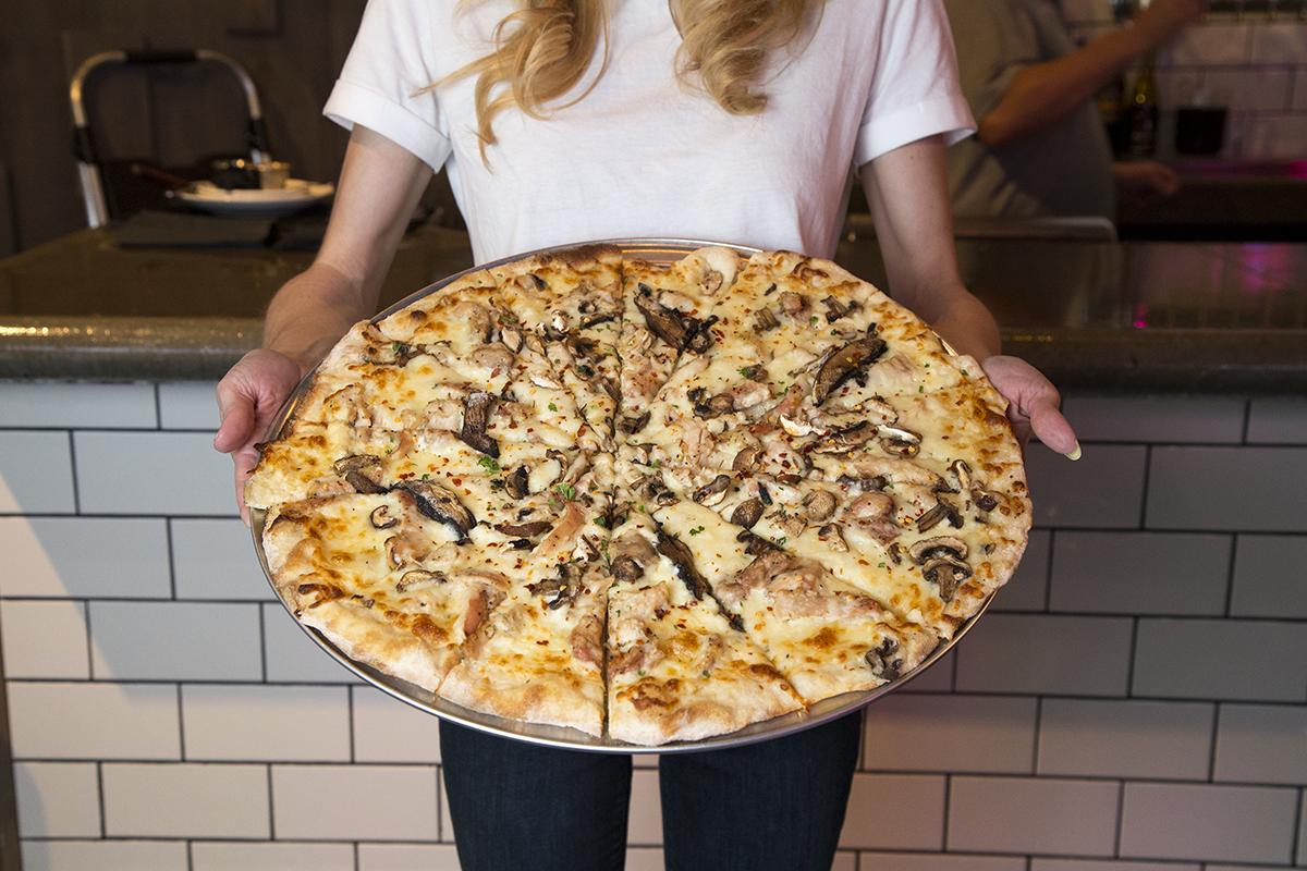 Girl holding a huge pizza