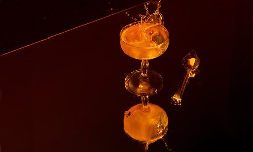 Tomato water Martini with droplets on mirror surface.