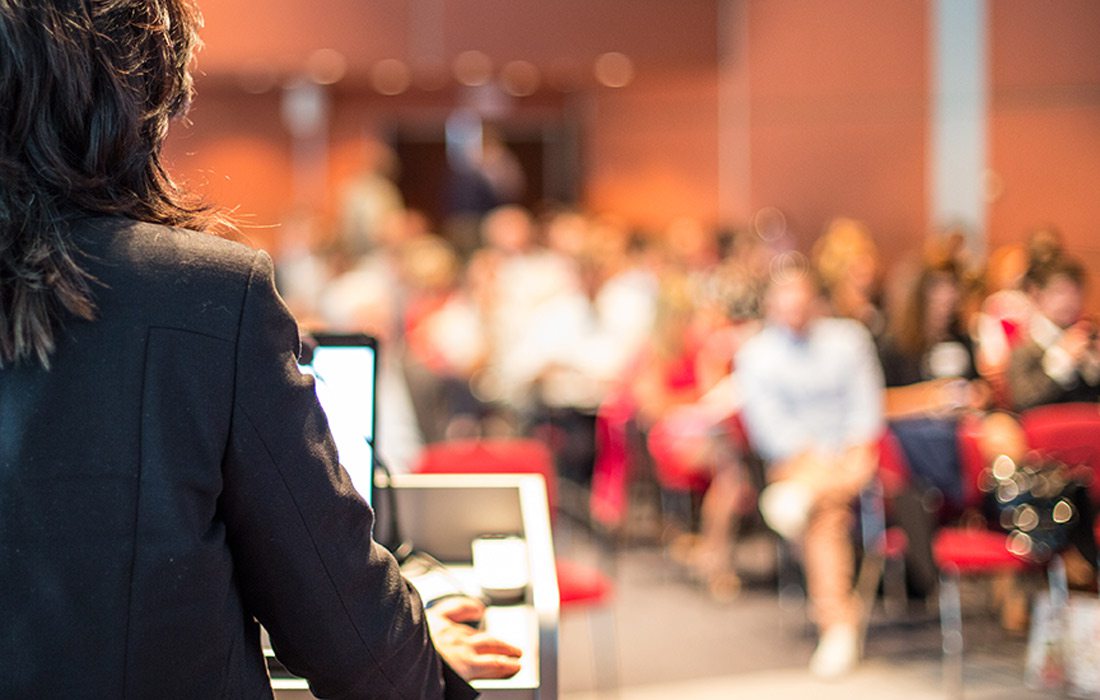 Businesswoman giving a speech to a room full of people.