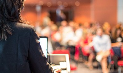 Woman giving a speech for a room full of people