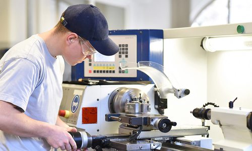 young apprentice in vocational training working on a turning machine in the industry