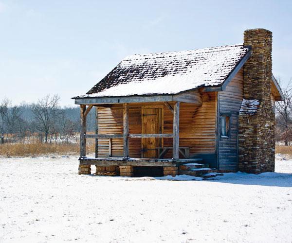 Snow-covered cabin in field during winter.