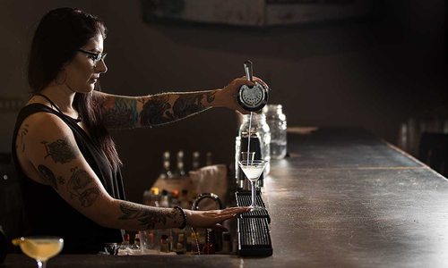 The bar tender pours the final toper on the Gin Gardens drink