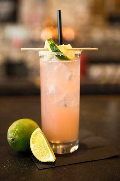 The Habanero de Jalisco drink sits on the counter top with slices of lime sitting next to it and perched on the rim