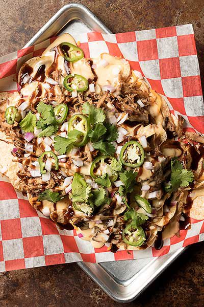 Smoked Pig Nachos covered in jalapeños, creamy cheese, pork