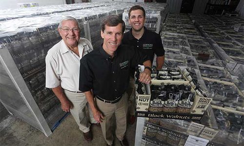 Dwain, Brian, and Jacob standing in front of their extensive store of black walnuts