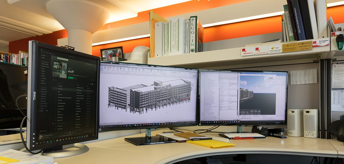 Computer screens in modern office with architecture plans.