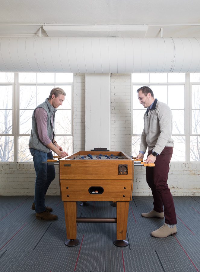 Employees playing foosball in bright, open office